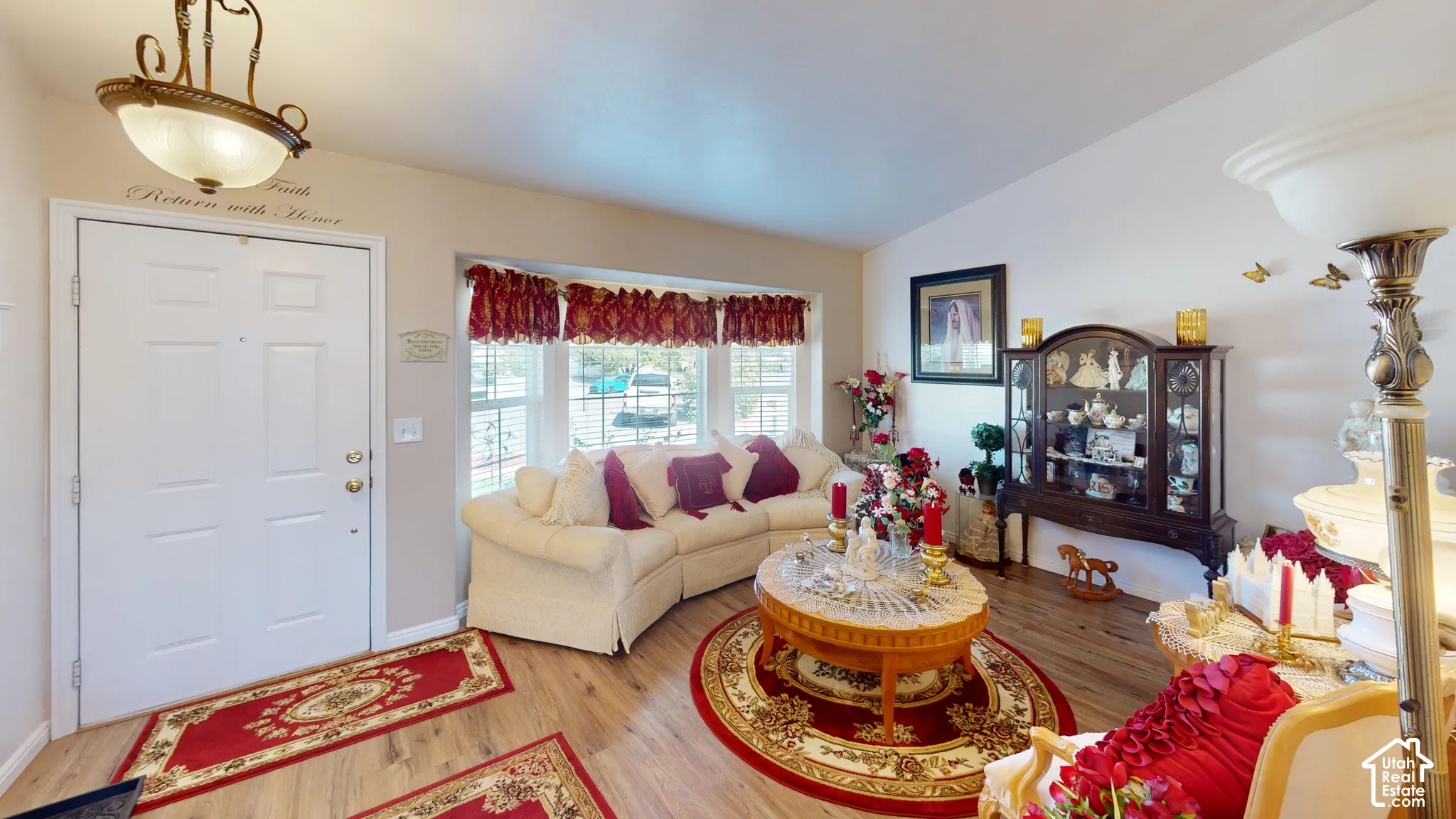 Vaulted ceiling, wood-finish flooring, bay window, white walls, and an overhead decorative light fixture