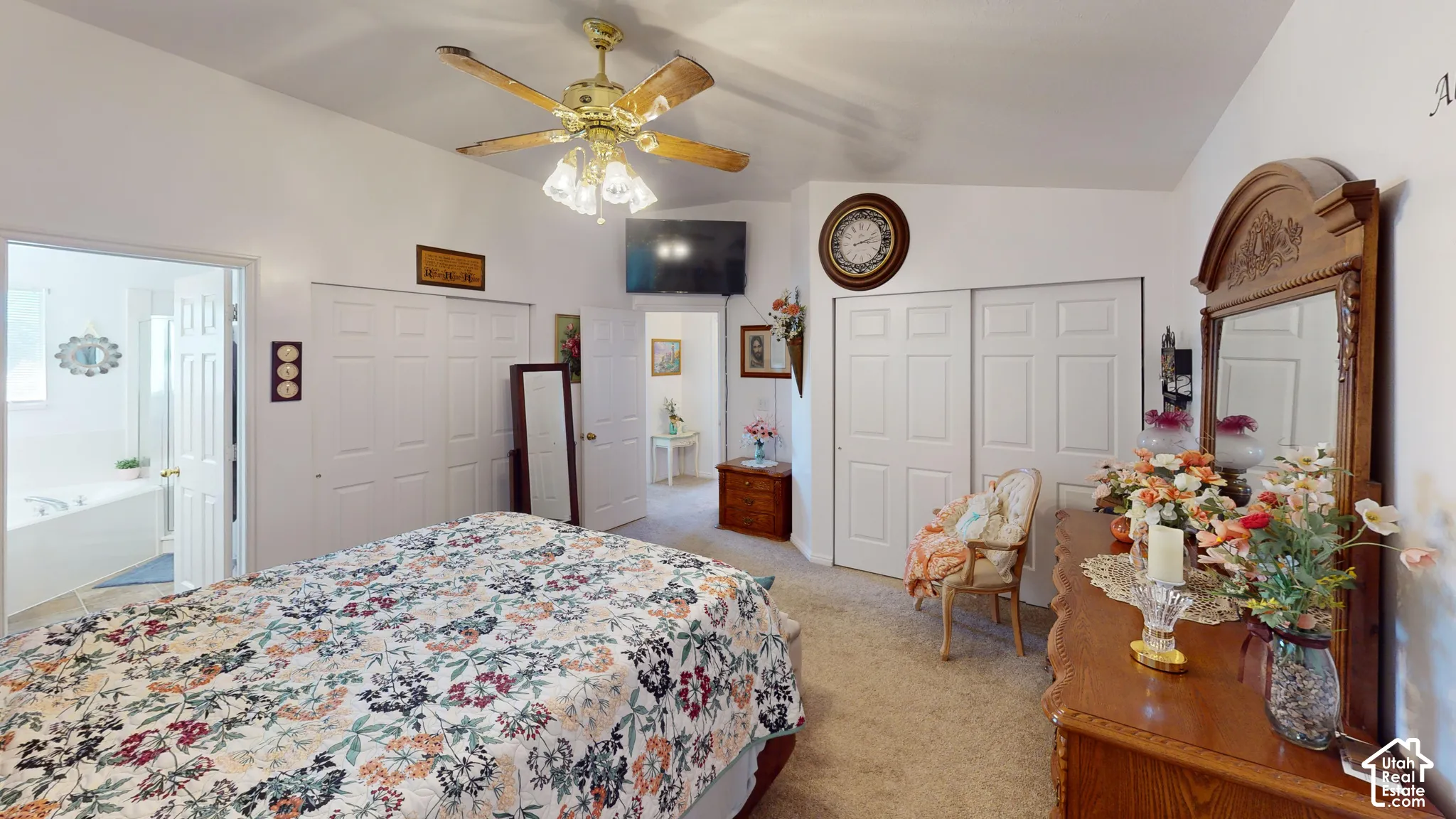 Vaulted ceiling with a ceiling fan, carpeted flooring, and white bi-fold closet doors