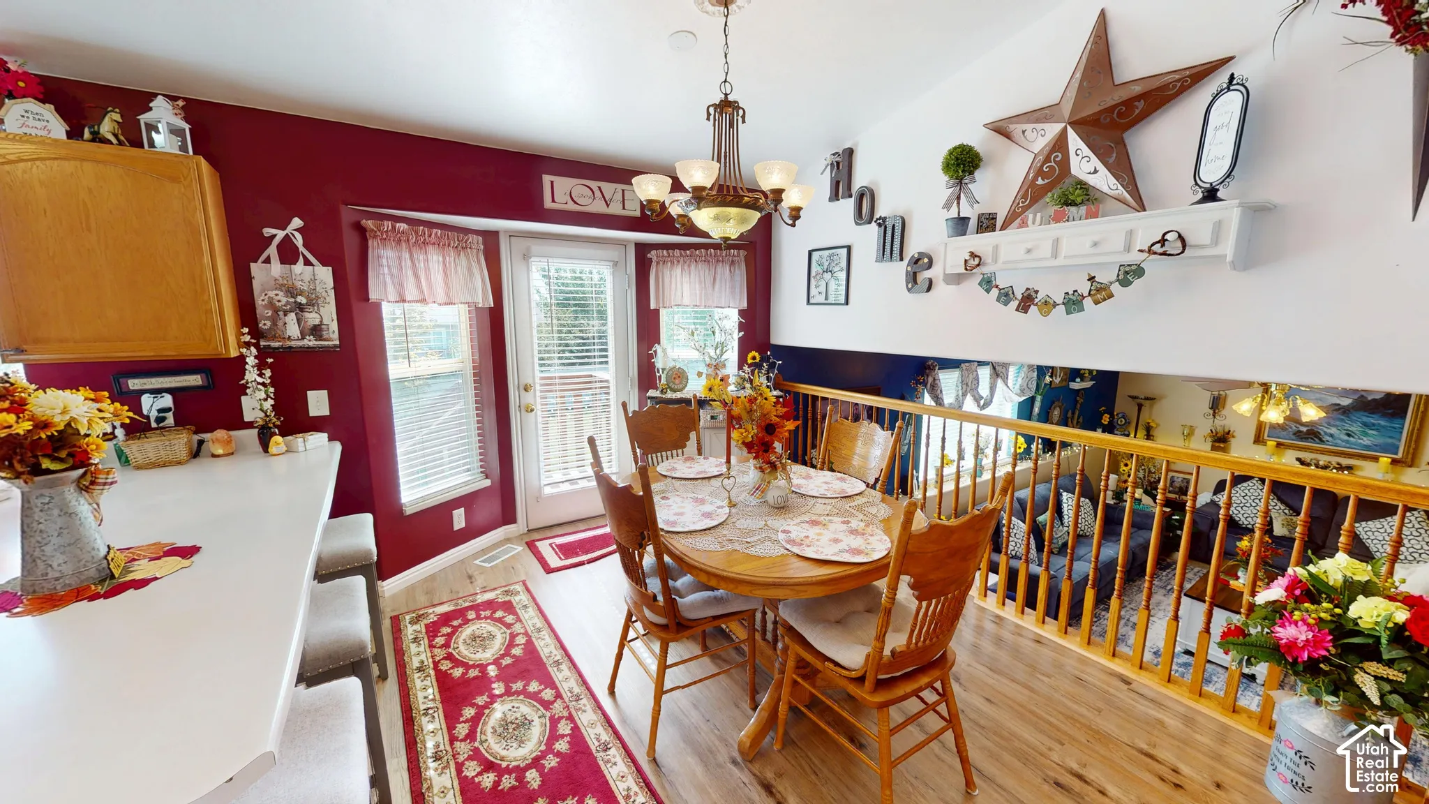 Dining area with wood-finish flooring, a decorative chandelier, and a bay window featuring a glass-paned door