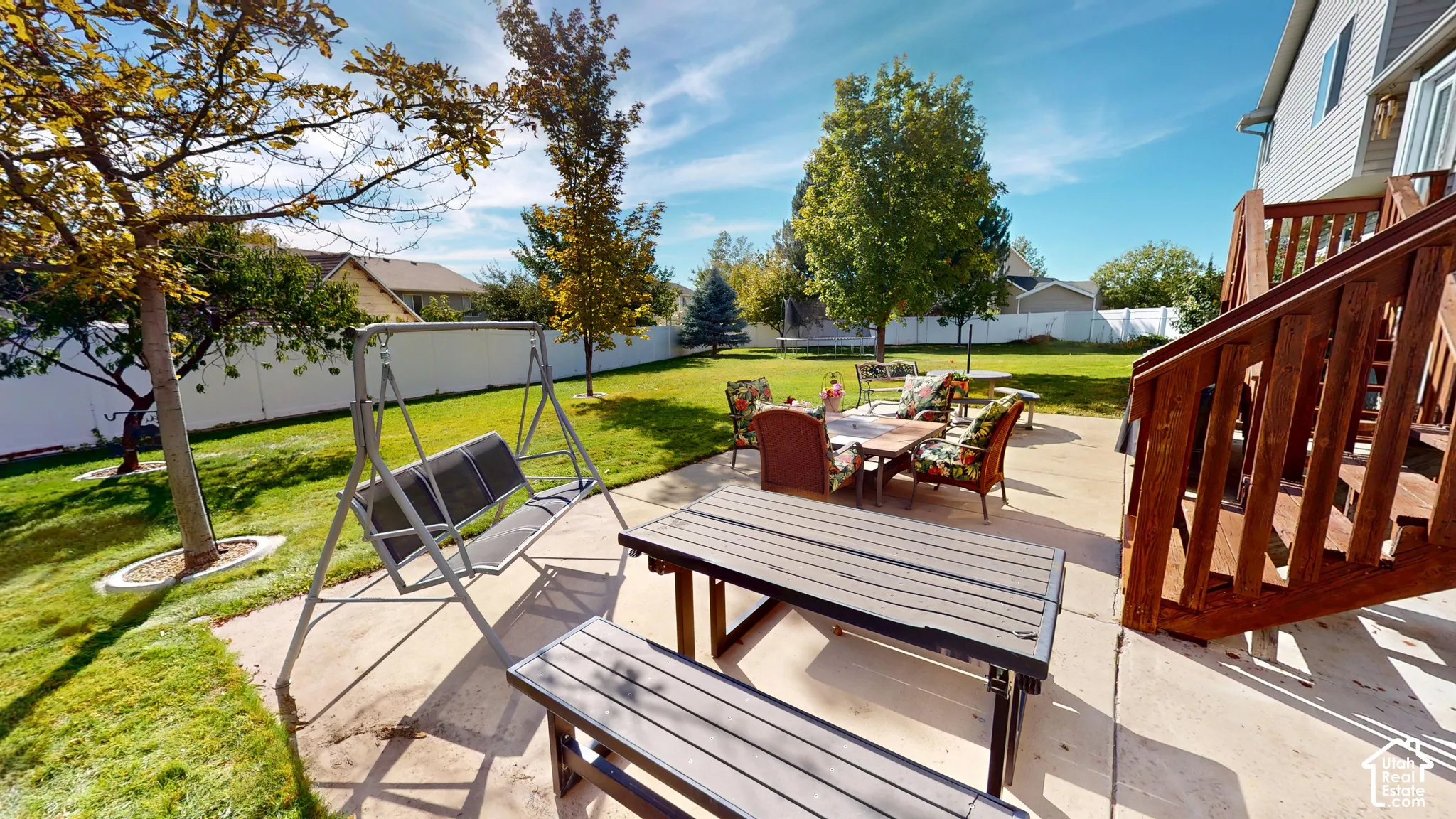 Expansive backyard with a manicured lawn, concrete patio, and mature trees