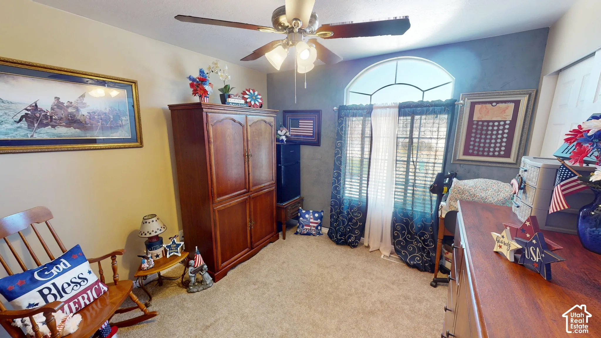 Arched transom window, flush mount ceiling fan, textured wall treatment, and light-colored carpet