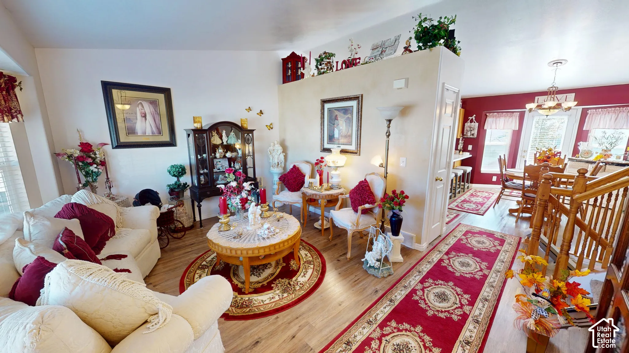 Wood-finish flooring throughout, featuring a half-wall partition and a visible dining area with a chandelier