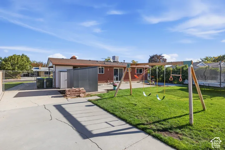 Expansive backyard featuring a manicured lawn, concrete patio, and brick exterior