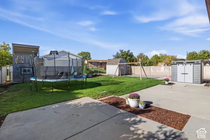 Expansive green lawn, concrete patio, perimeter fencing, and a built-in outdoor storage shed
