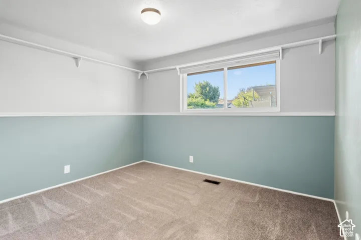 Wall-to-wall carpet flooring, dual-tone painted walls, and a ceiling-mounted light fixture