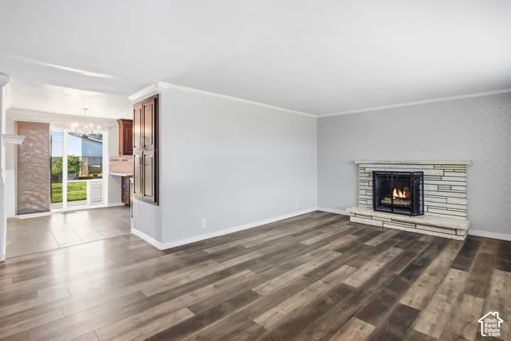 Wood-finish flooring throughout, stone fireplace with hearth, built-in cabinetry, crown molding, and sliding glass door