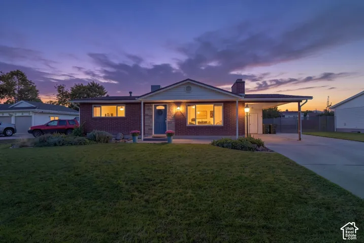 Brick exterior with stone accents, covered carport, integrated chimney, and a well-maintained lawn