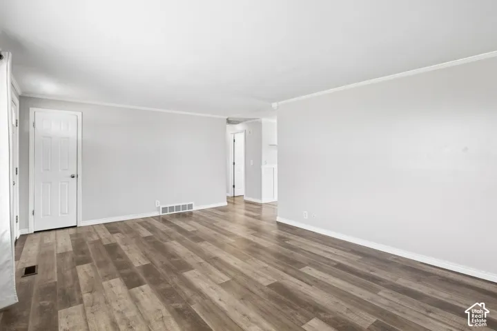 Wood-finish flooring throughout, light gray walls, white trim, and a paneled interior door