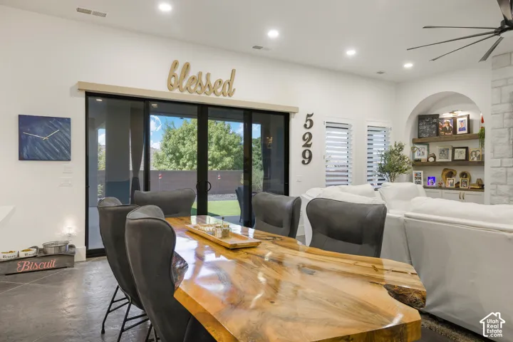 Sliding glass door to the exterior, recessed lighting, arched built-in shelving, white cabinetry, and stone-finish wall accent