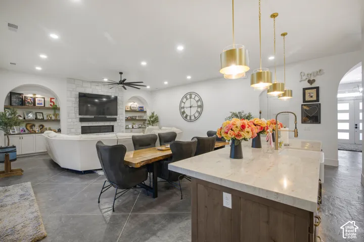Kitchen island with light-toned countertop, wood-finish paneling, and gold-finish pendant lighting
