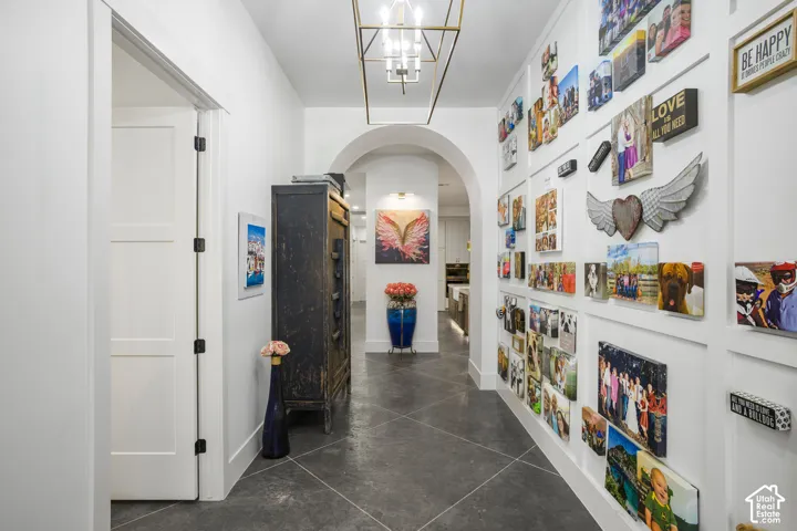 Archway entry with a modern chandelier and dark flooring