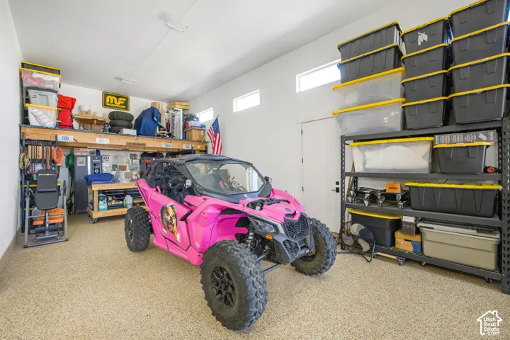 Spacious garage featuring a durable epoxy floor, built-in shelving, high ceilings, and transom windows