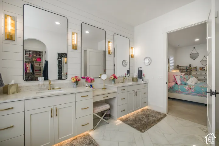 Dual vanity with undermount sinks, stone countertops, and gold-finish fixtures