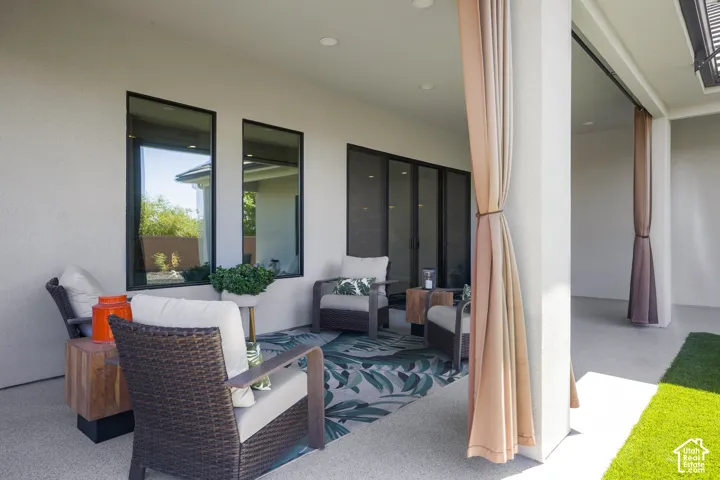 Covered patio with recessed lighting, large format sliding glass doors, multiple vertical windows, and privacy curtains