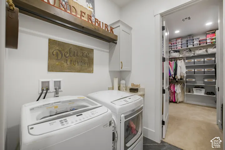 Laundry area featuring white cabinetry, a built-in countertop, and an adjacent walk-in closet with ample shelving and hanging rods