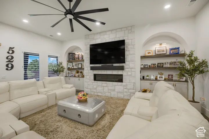 Stone-clad fireplace with an integrated linear firebox, custom built-in shelving, arched wall niches, and a large ceiling fan