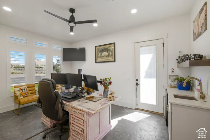 Recessed lighting, ceiling fan, multiple windows with plantation shutters, exterior access door, and an integrated wet bar with a countertop and sink