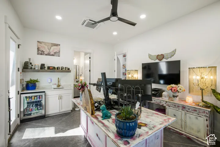 Ceiling fan, recessed lighting, built-in wet bar with beverage refrigerator, white cabinetry, and a floating wood-finish shelf