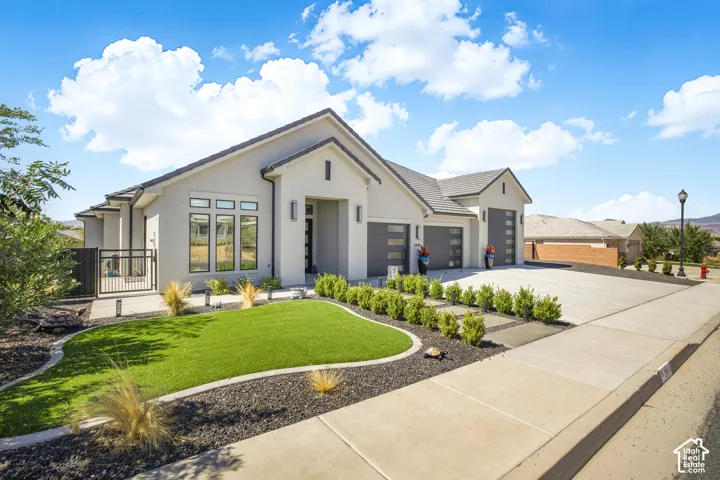 Contemporary stucco exterior with a tiled roof, three-car garage, and a concrete driveway