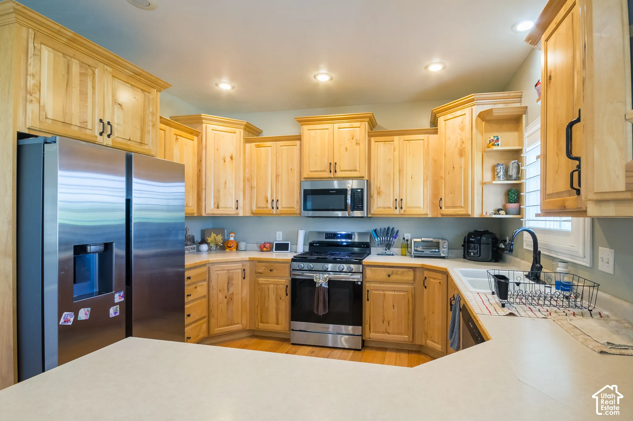 Kitchen featuring light wood cabinetry, light-toned countertops, and stainless steel appliances