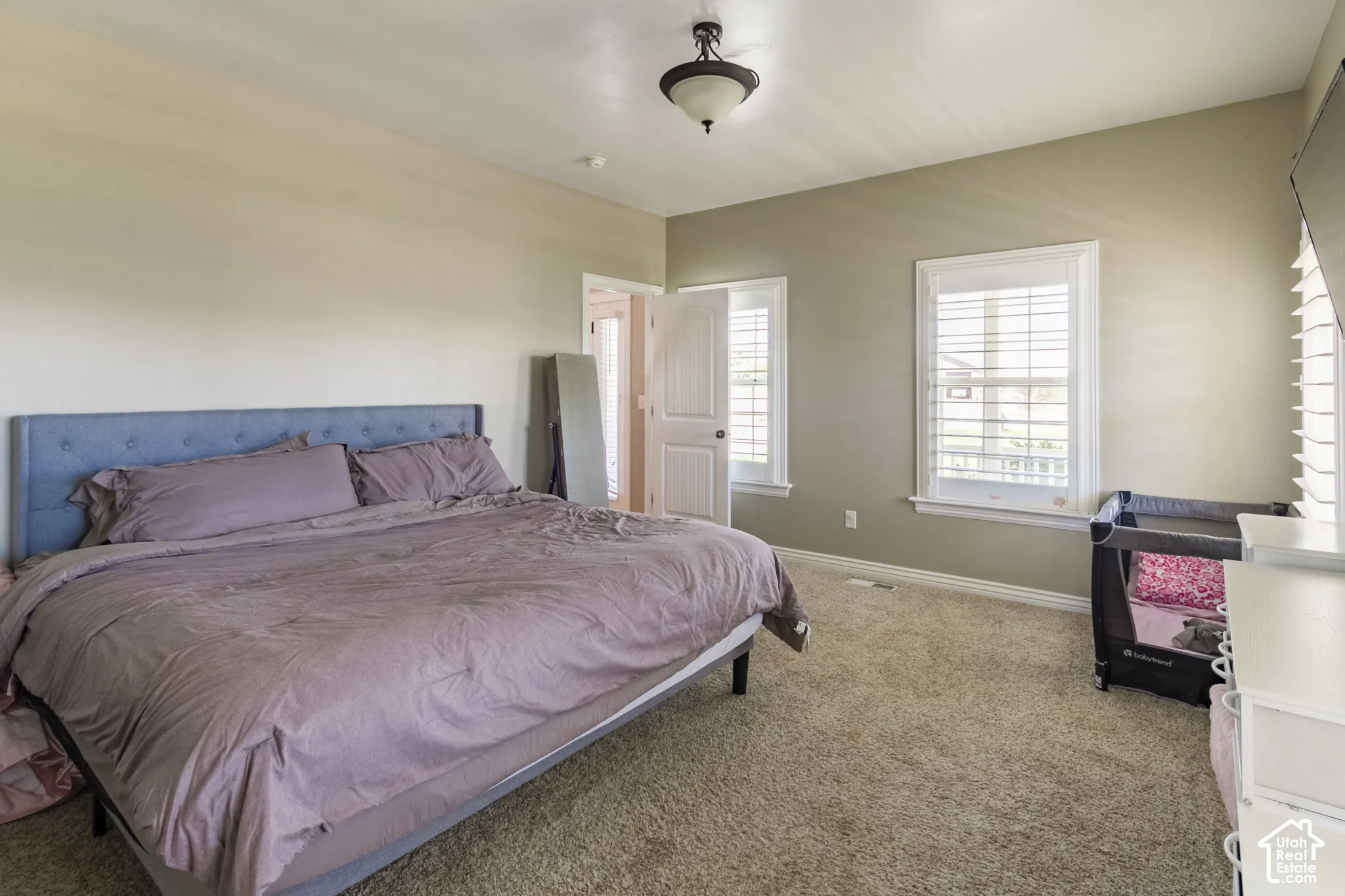 Neutral-toned walls, plush carpet flooring, two windows with plantation shutters, ceiling-mounted light fixture, and white trim throughout