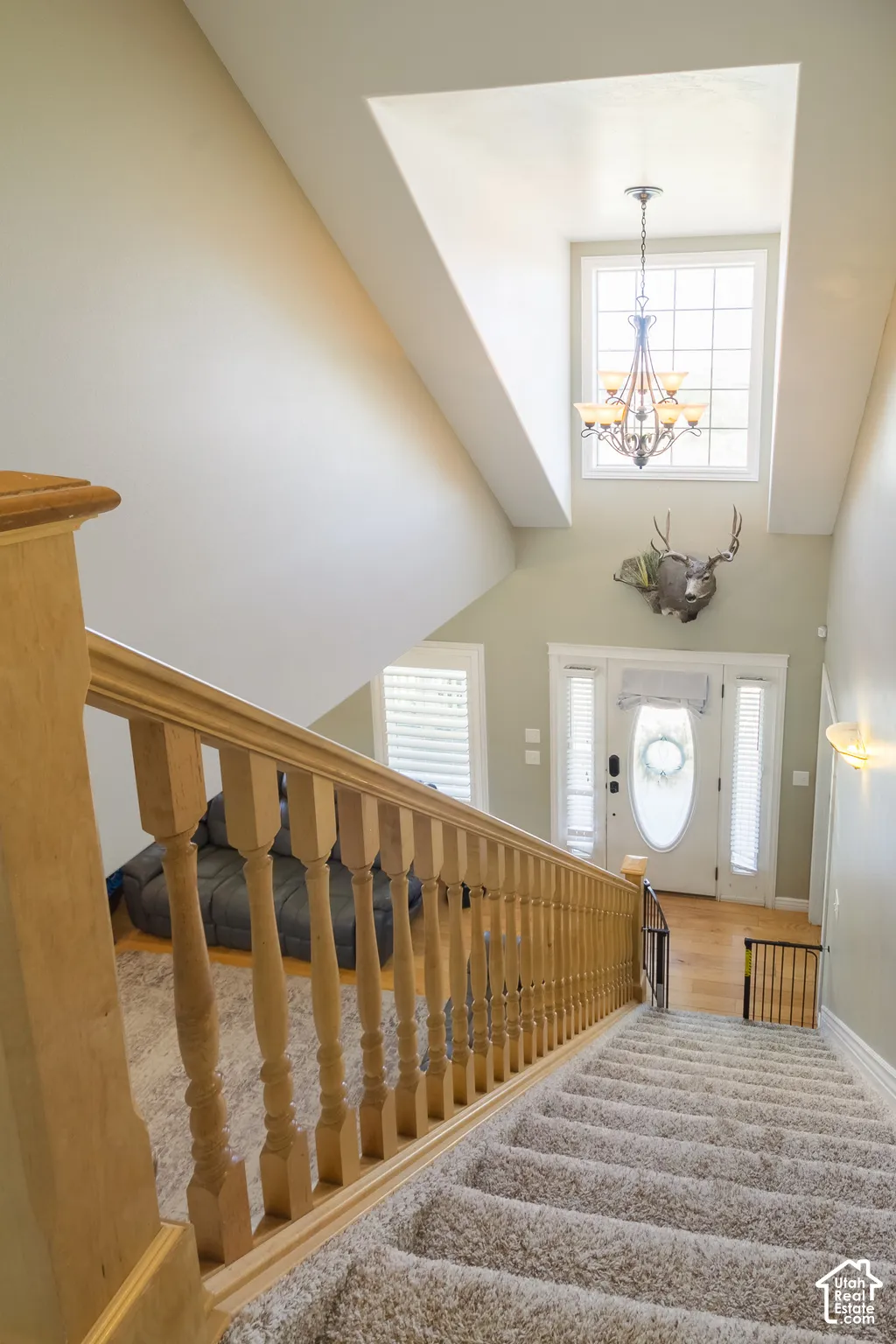 Vaulted ceiling with an upper window, chandelier, wood-finish flooring, and a staircase with wood railing