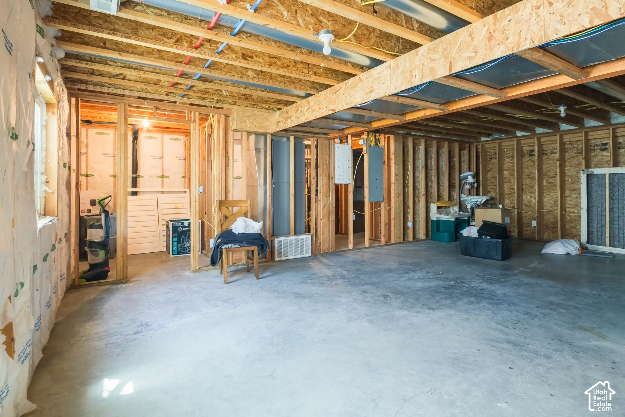 Unfinished basement with exposed wood framing, concrete flooring, and visible ceiling joists