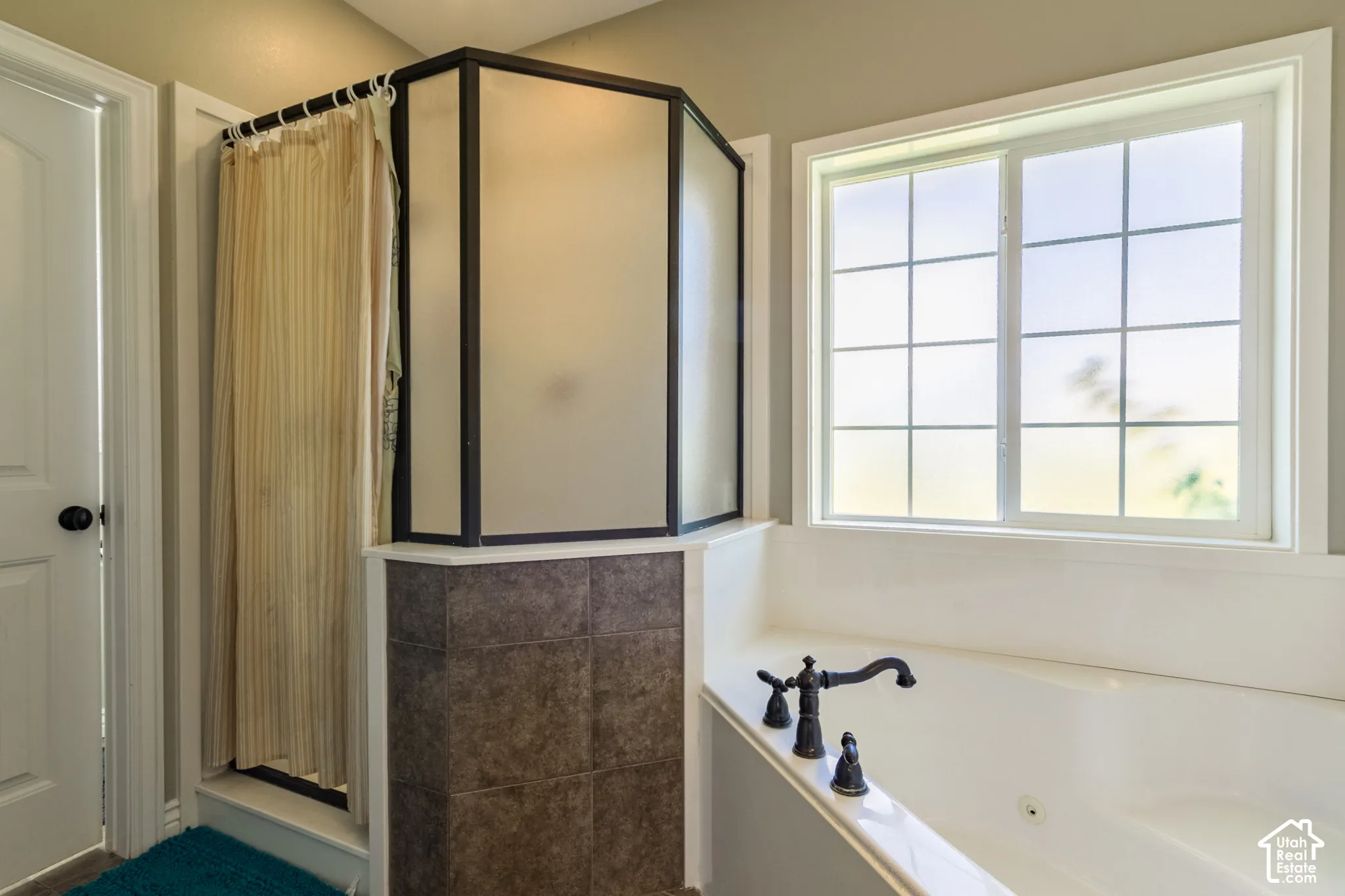 Built-in soaking tub with dark-toned fixtures and a grid-paned window