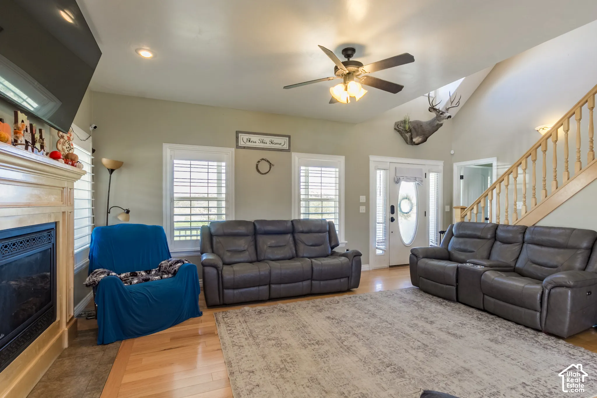 Vaulted ceiling living area featuring a fireplace with a wood-finish mantel, recessed lighting, and wood-finish flooring