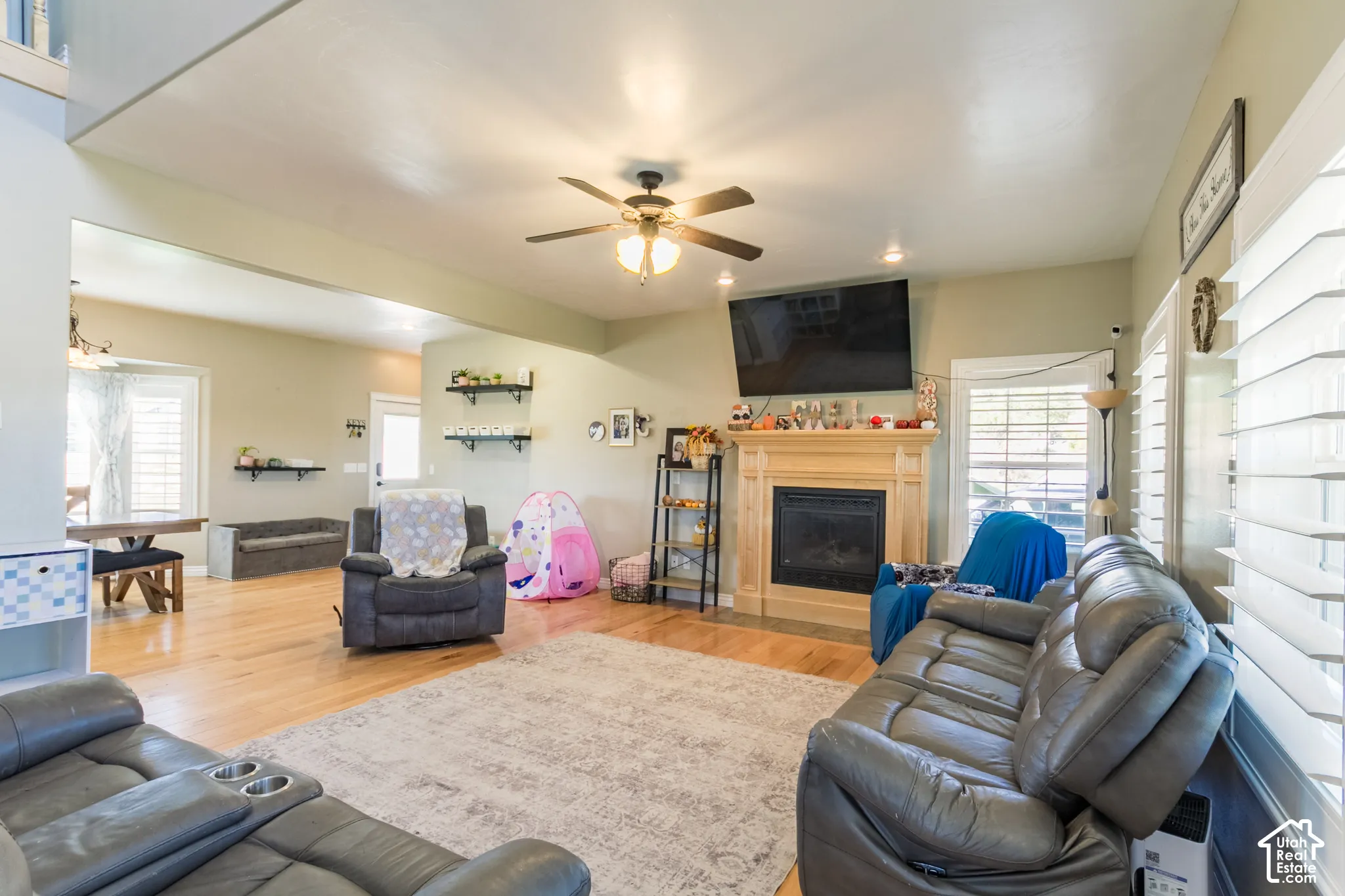Hardwood flooring, ceiling fan, recessed lighting, and a fireplace with a wood mantel