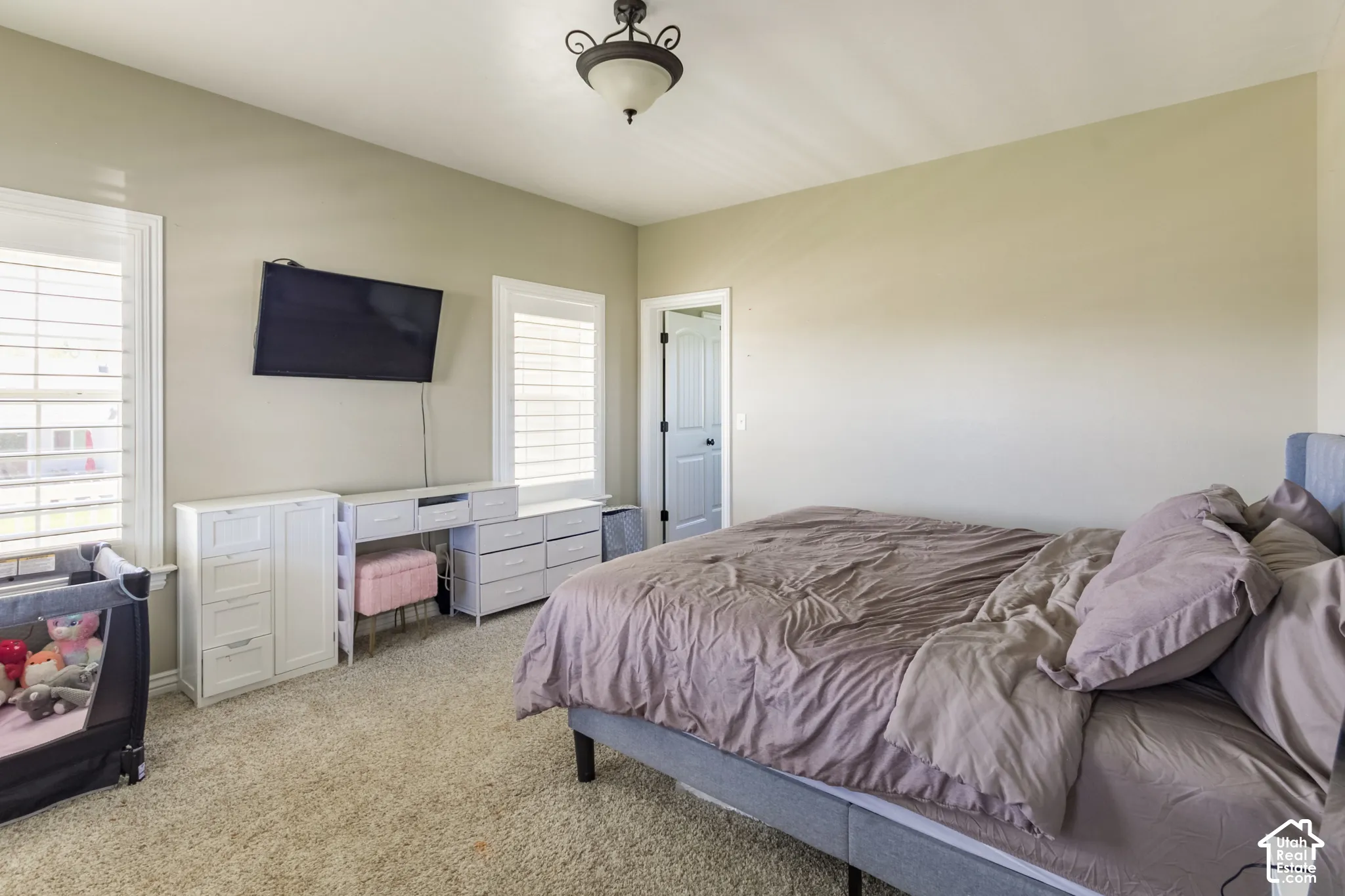 Vaulted ceiling, two windows with plantation shutters, wall-mounted television, and a built-in light fixture