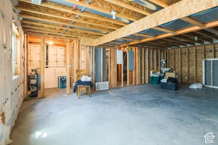 Unfinished basement with exposed wood framing, concrete flooring, and visible ceiling joists