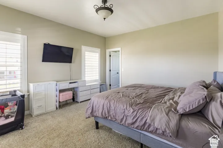 Vaulted ceiling, two windows with plantation shutters, wall-mounted television, and a built-in light fixture