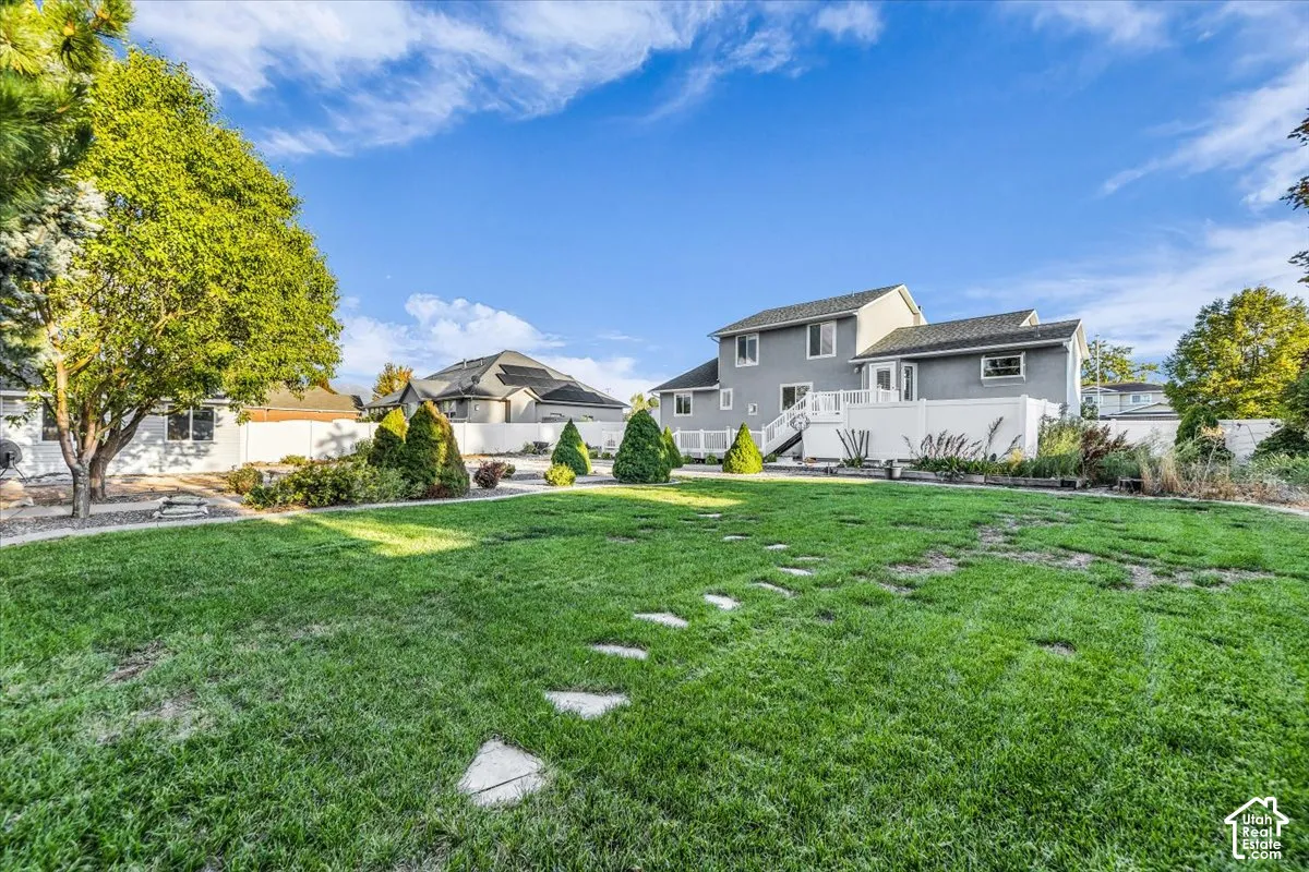 Expansive green lawn with stepping stones, mature trees, and beautiful landscaping