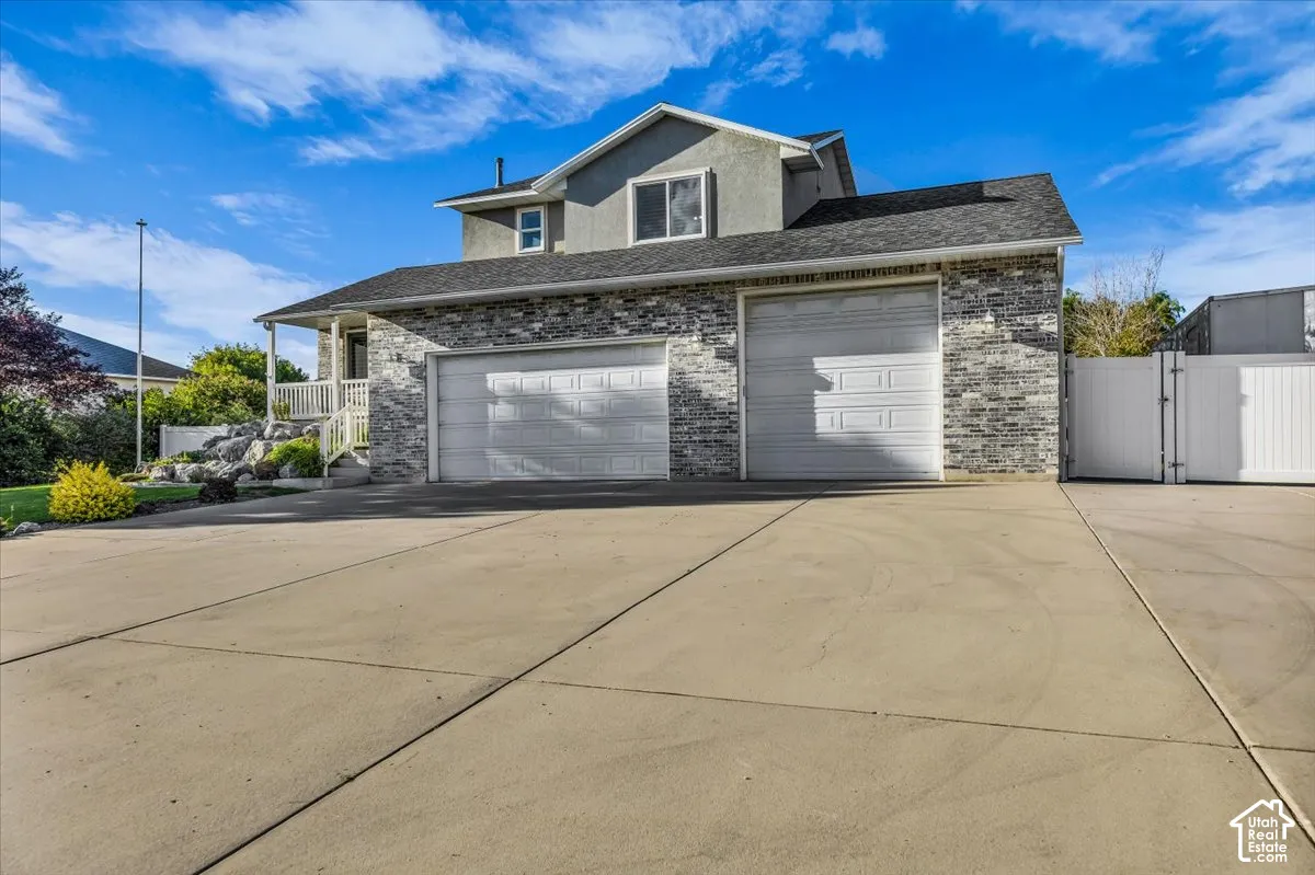 Exterior featuring a 3-car garage, stone and stucco, concrete driveway, and a covered porch with white railings
