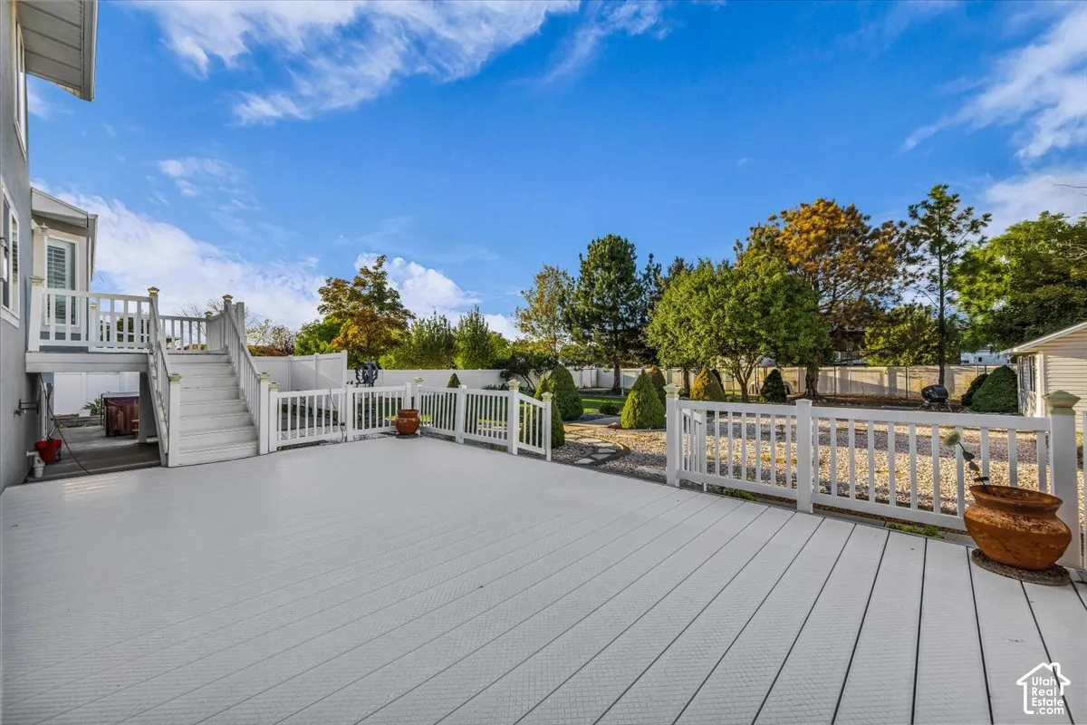 Expansive outdoor vinyl decking with multi-level access, featuring white railings and mature perimeter landscaping