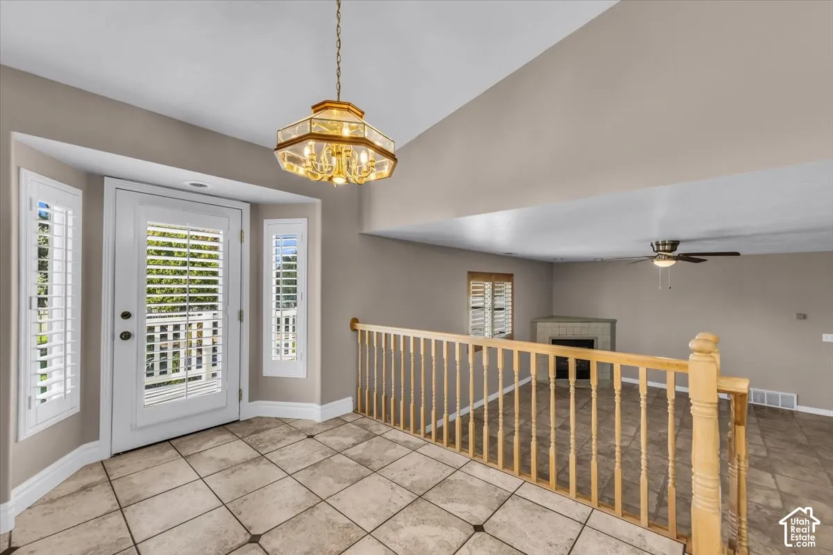 Bay window and door with plantation shutters, tile flooring, and a decorative chandelier