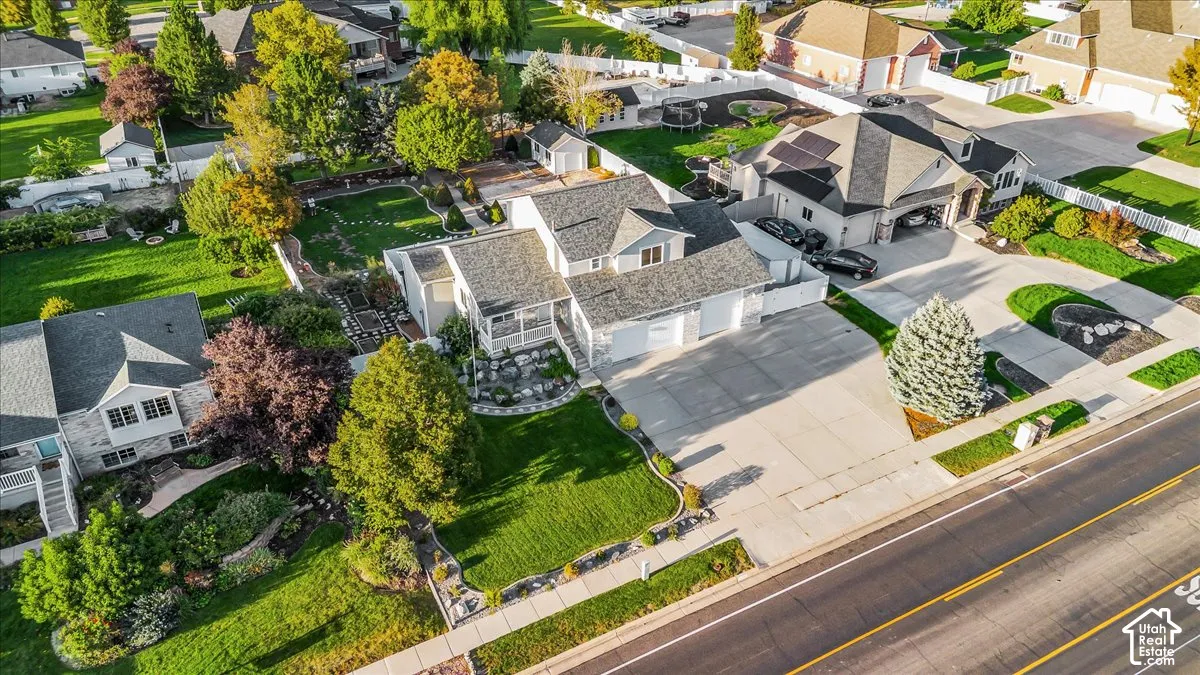 Expansive property featuring a multi-level structure, a spacious driveway, a meticulously landscaped yard with mature trees, and a detached shed