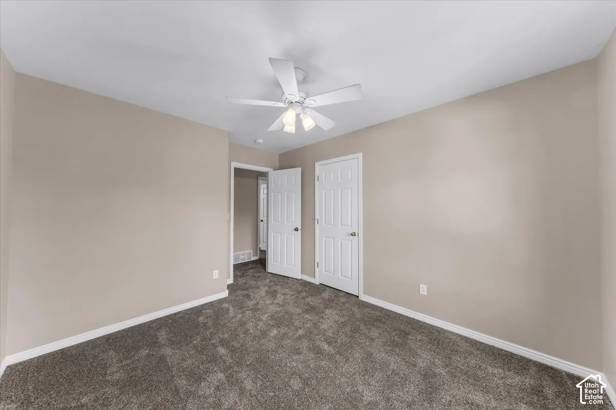 Neutral-toned walls, textured carpeting, white trim, and a ceiling fan with integrated lighting