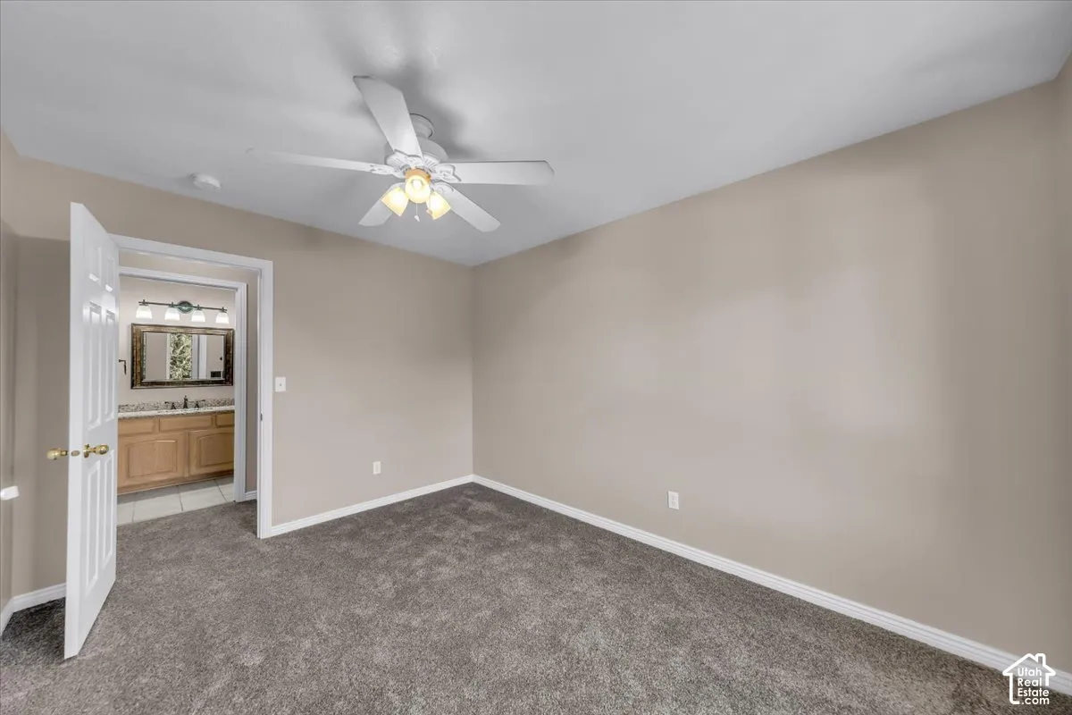 Neutral tone walls with white trim, carpet flooring, and a ceiling fan with integrated lighting