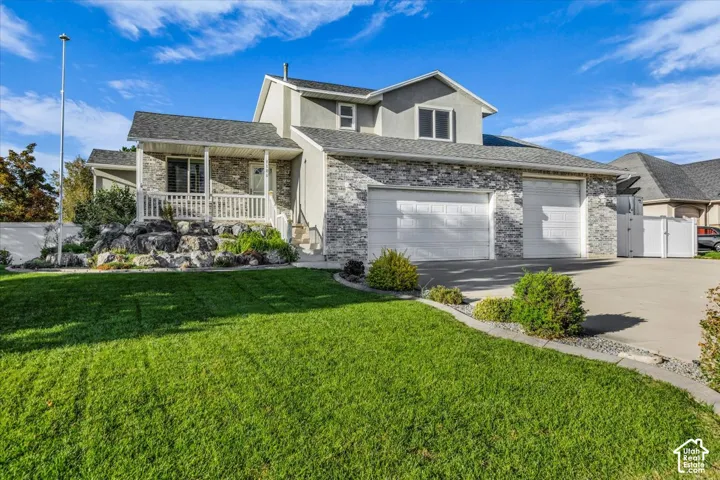 Exterior featuring brick and stucco finishes, a covered front porch with white railing, a 3 car garage, and landscaped rock gardens