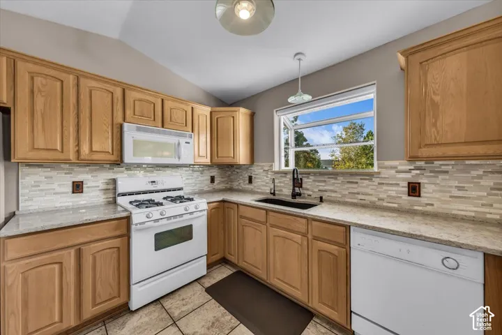Kitchen featuring wood cabinetry, light-toned quartz countertops, a glass tile backsplash, and a box window with natural light