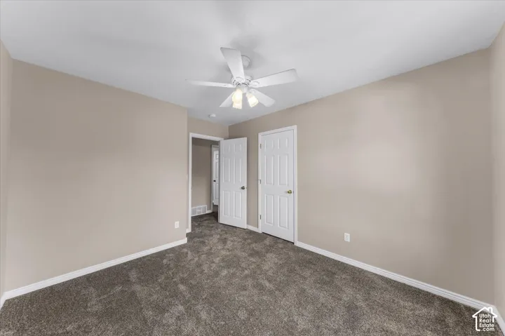 Neutral-toned walls, textured carpeting, white trim, and a ceiling fan with integrated lighting
