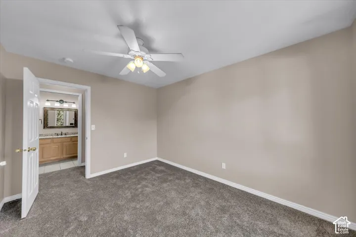 Neutral tone walls with white trim, carpet flooring, and a ceiling fan with integrated lighting