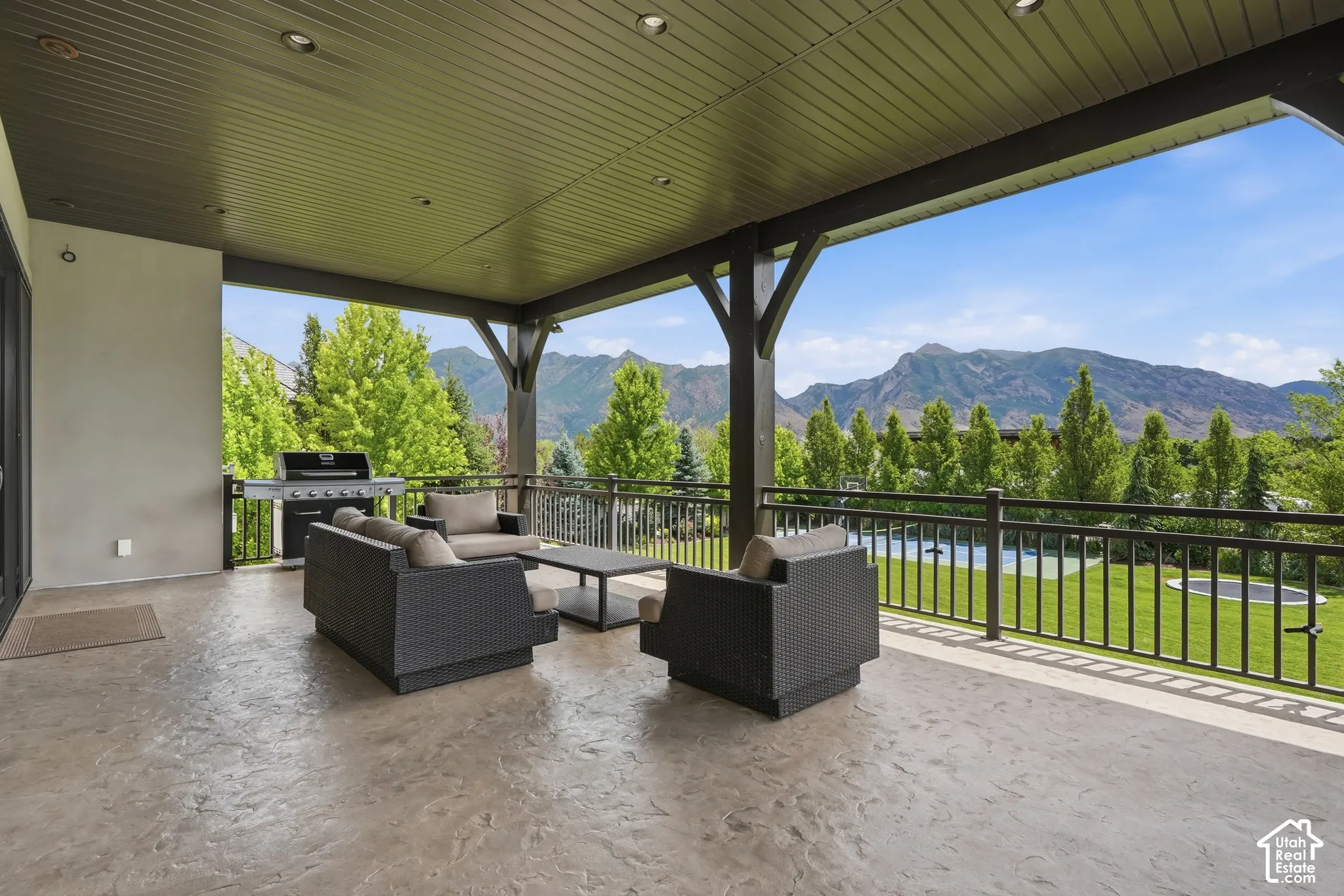 Covered patio with stamped concrete flooring, recessed lighting, and a dark railing system