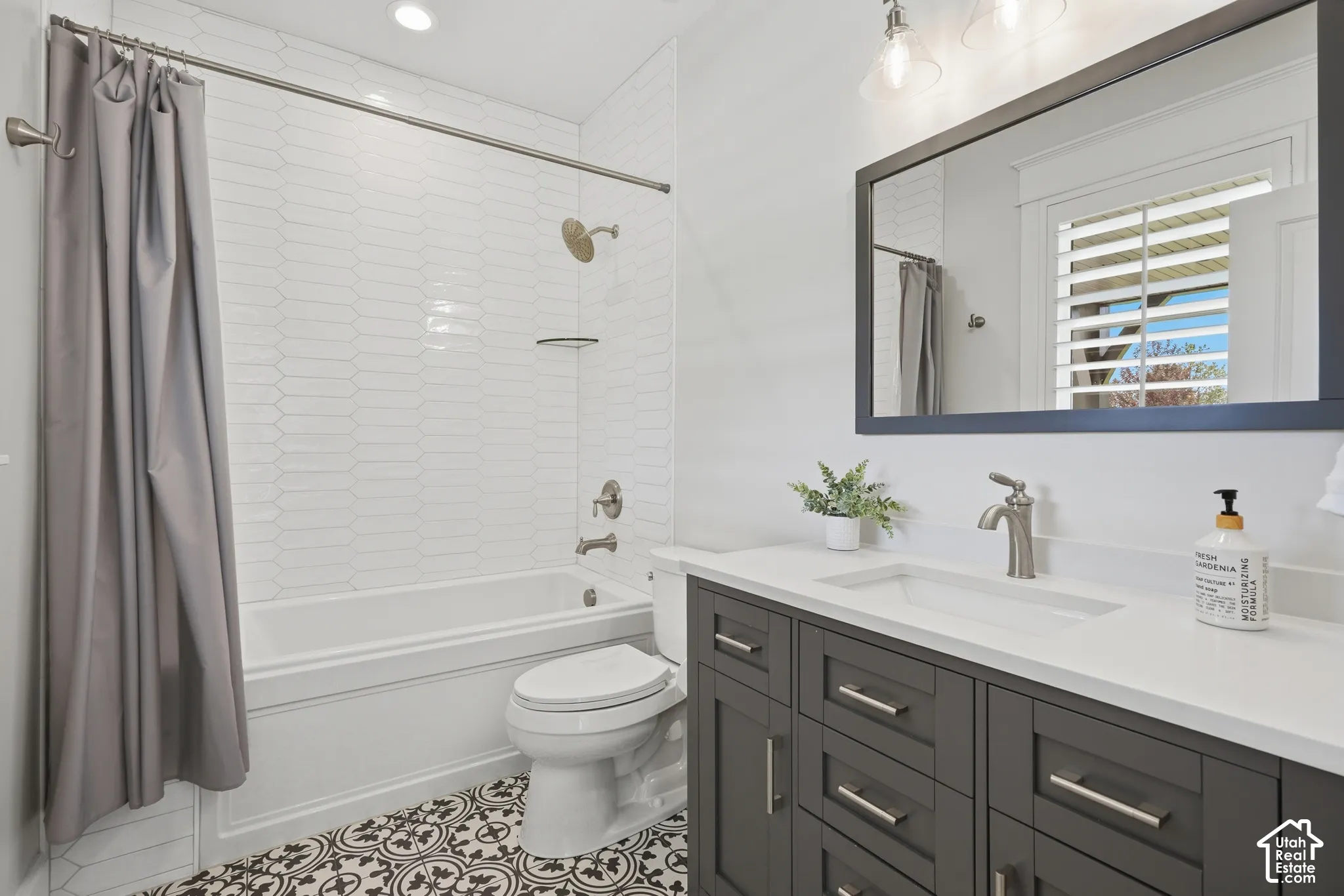 White subway tile shower surround with a built-in tub, patterned floor tile, and a dark wood-finish vanity with a white countertop