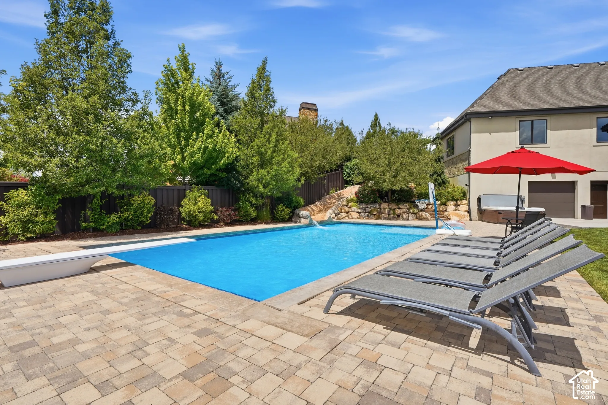 Expansive paver patio surrounding a swimming pool with a diving board