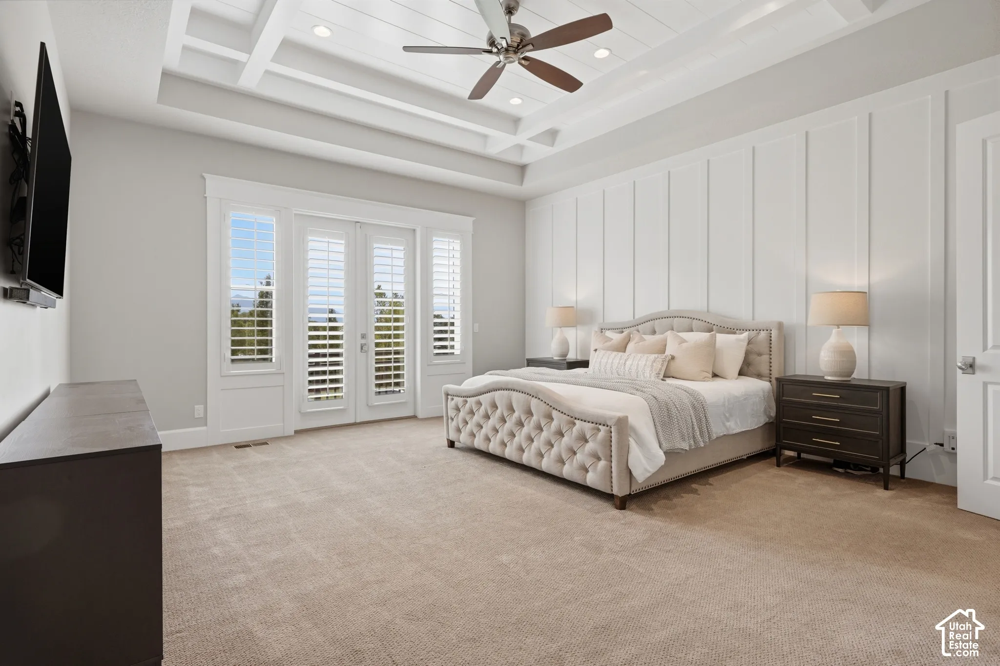 Coffered ceiling with a ceiling fan, wall paneling, double doors with interior shutters, and carpet flooring