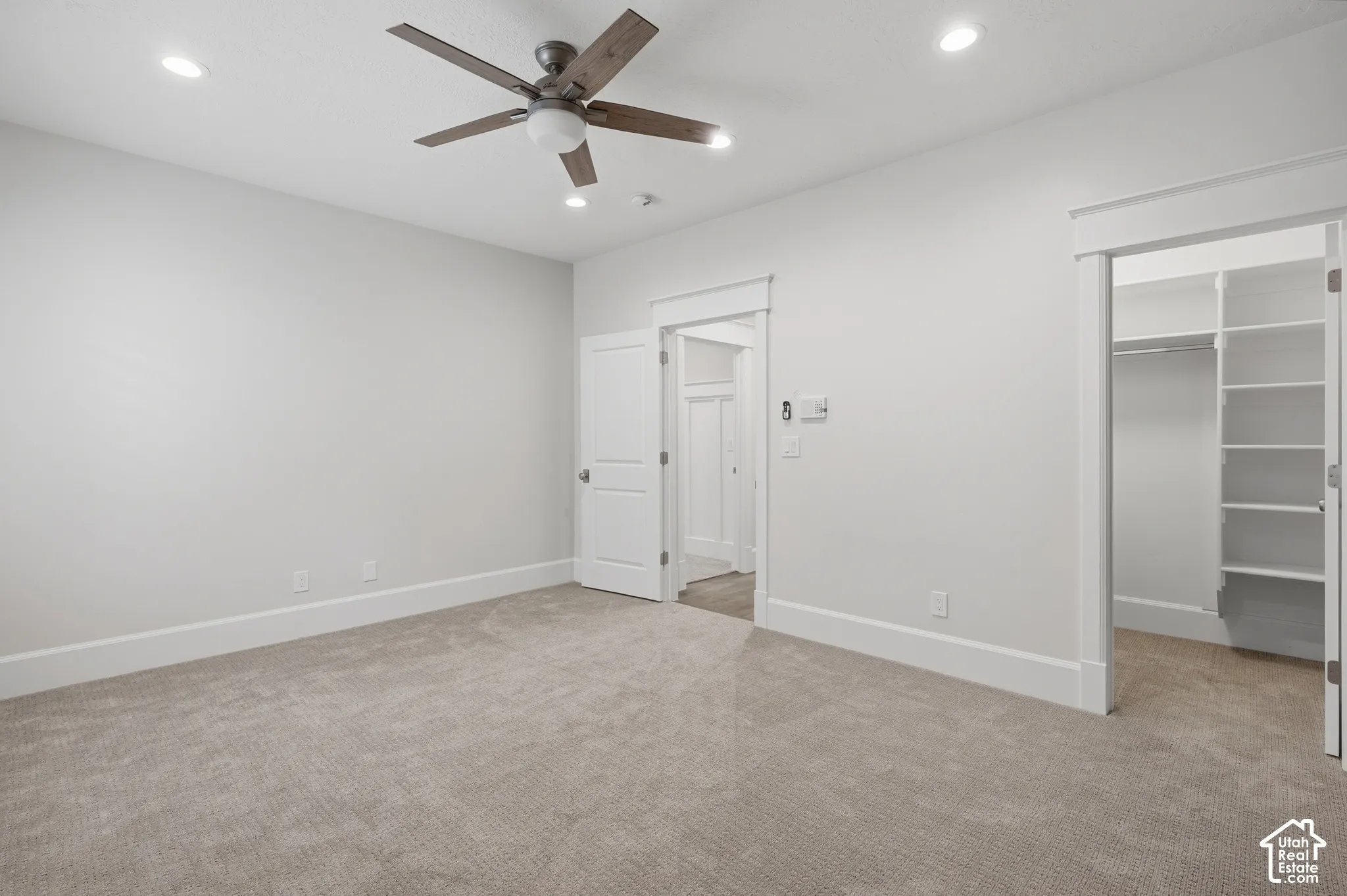 Plush carpeting, recessed lighting, and a ceiling fan with integrated light