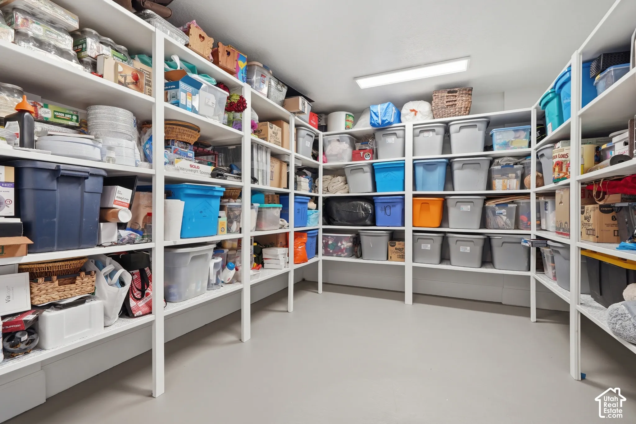 Expansive storage area featuring extensive built-in shelving, durable flooring, and overhead lighting